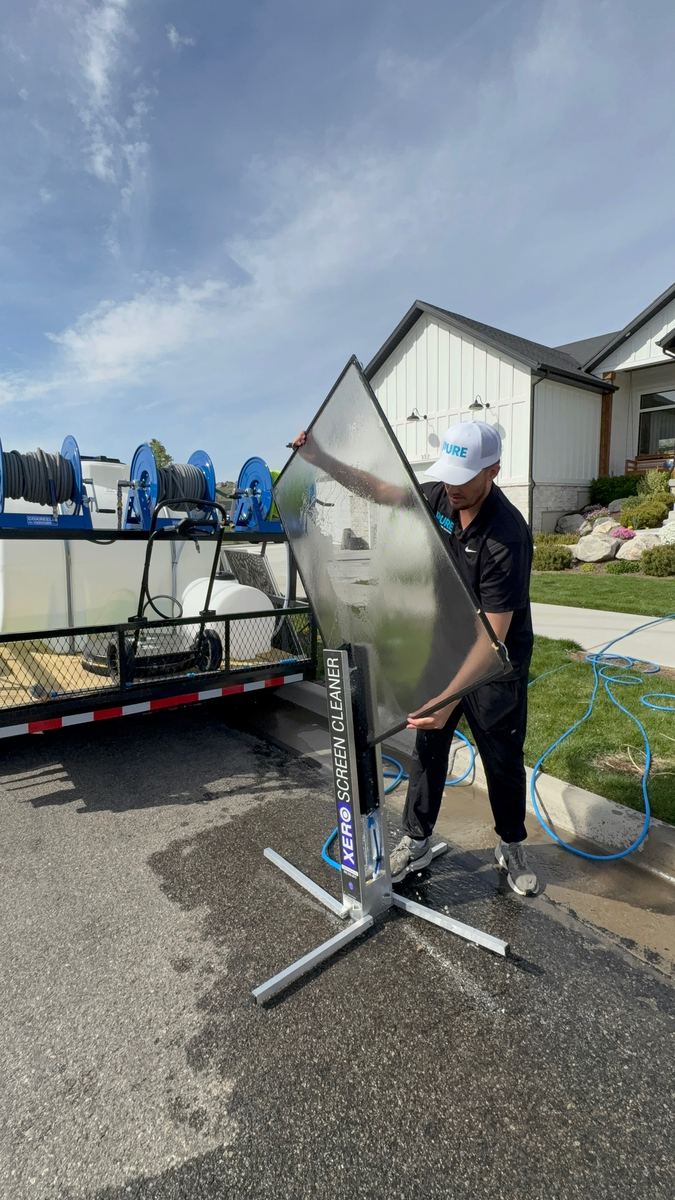 Window screen being cleaned on a XERO Screen Cleaner stand in a driveway