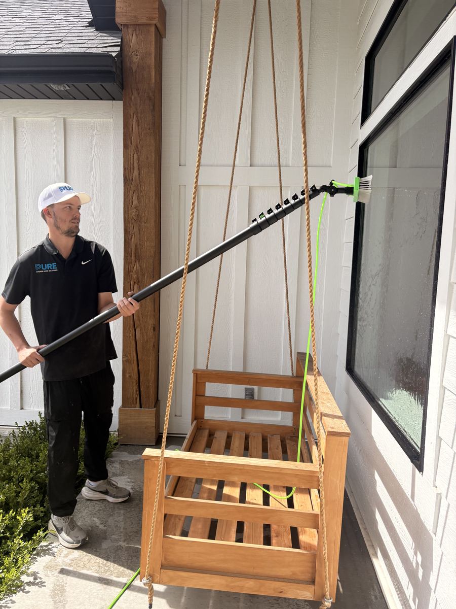 Water-fed pole cleaning a transom window above a garage door