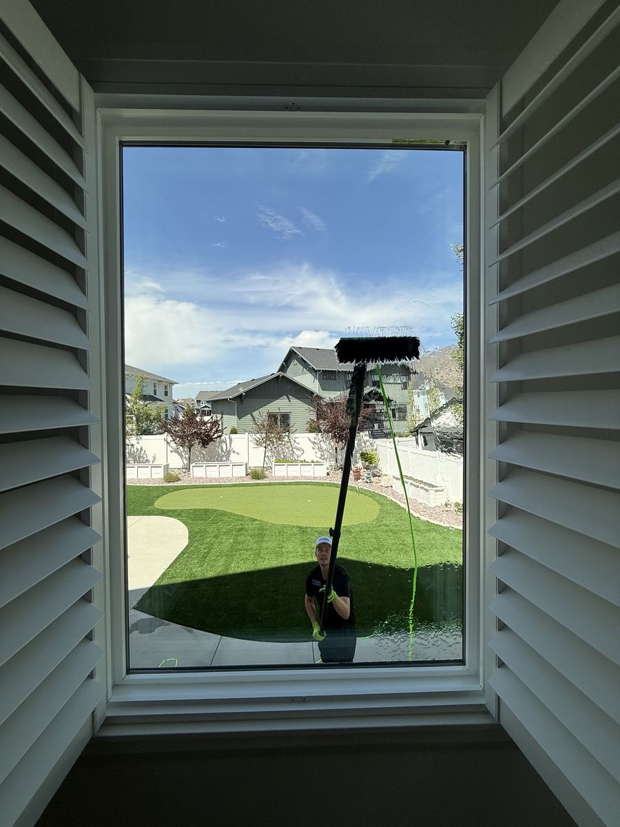 View from inside a home looking through a spotlessly clean large picture window at a suburban neighborhood and blue sky